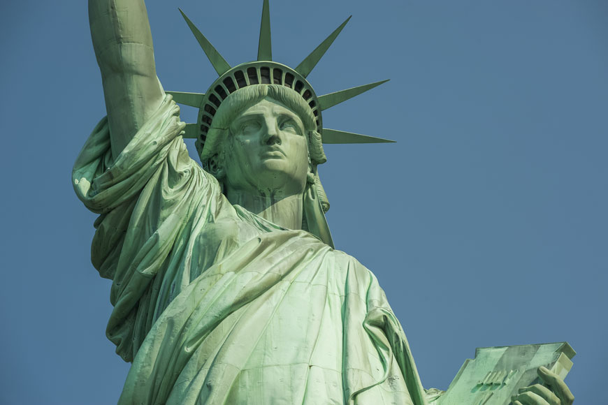 The bust of the American Statue of Liberty is captured in front of a blue sky