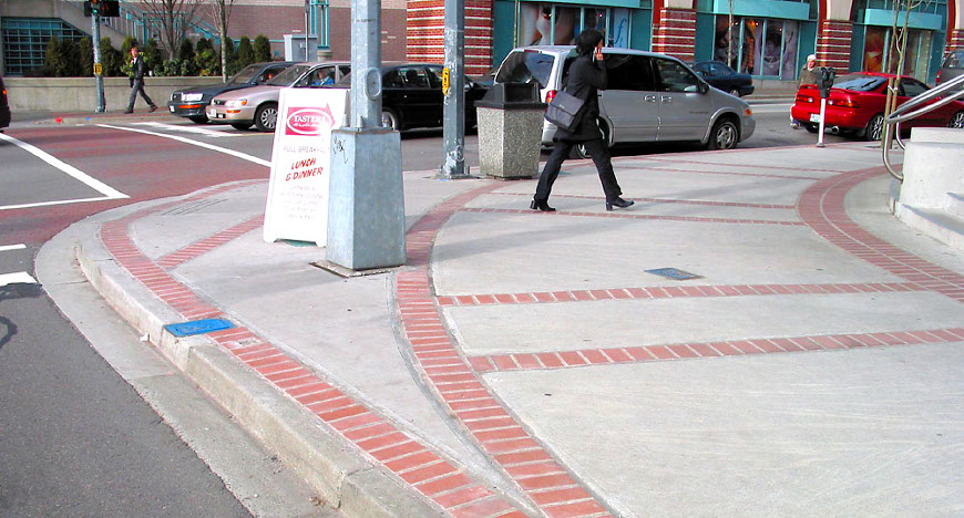 Esquina de acera extendida cerca de una calle concurrida