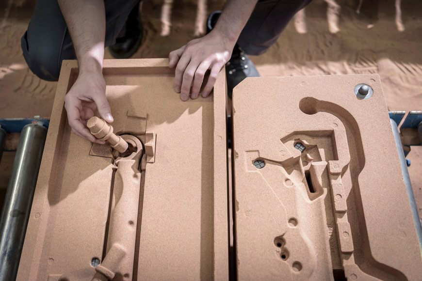 A foundry worker inserting cores into a no-bake sand mold