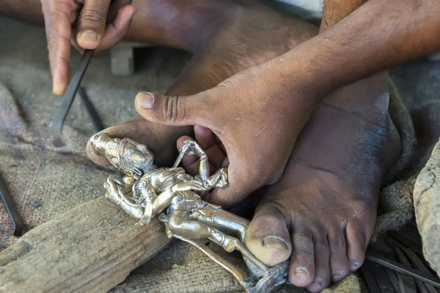 Foundry worker cleaning up an aluminum statue after it was removed from mold