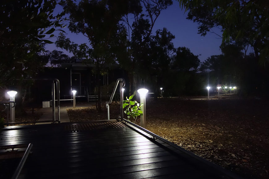 Outdoors at night under a purple sky, lights dotting a deck and pathway