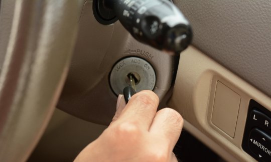 Hand putting car key on the keyhole