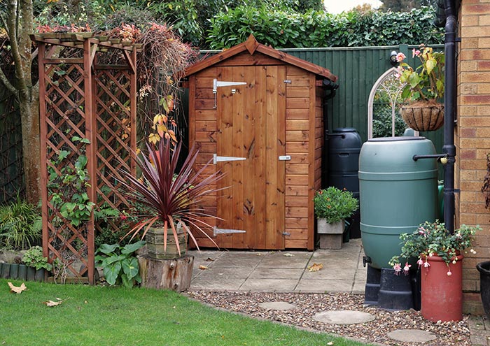 Backyard rainscape with rain barrel garden shed and potted plants.